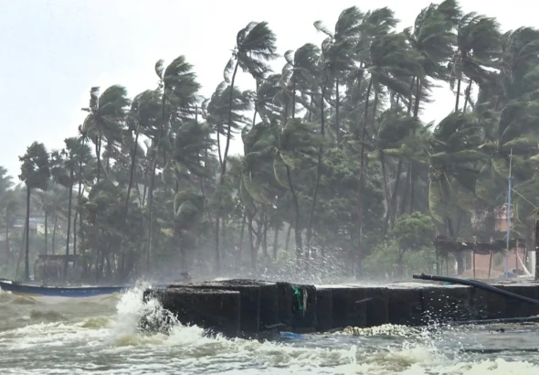 strong-winds-bend-palm-trees-and-waves-crash-against-a-seawall-during-rough-sea-conditions-triggered-305443123-16x9_0